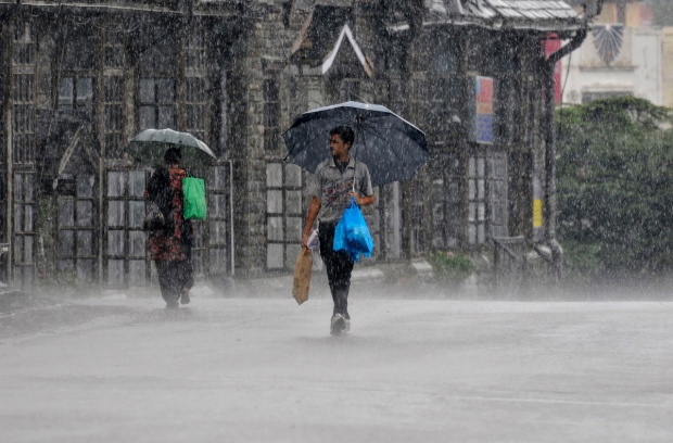 People hold umbrellas as they walk in heavy rain in Shimla